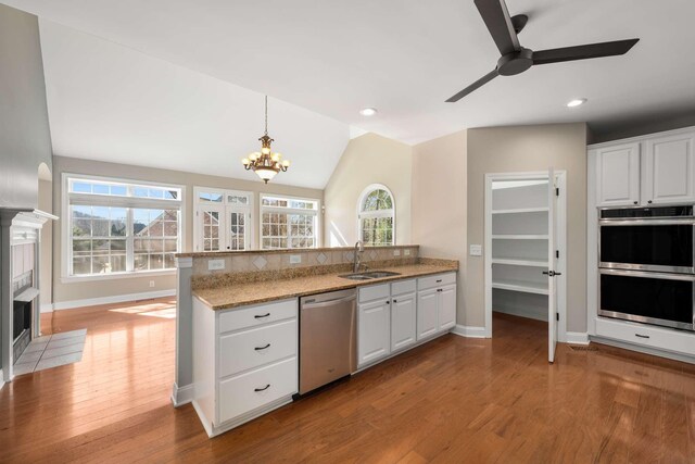 kitchen featuring a peninsula, white cabinets, stainless steel appliances, and a sink