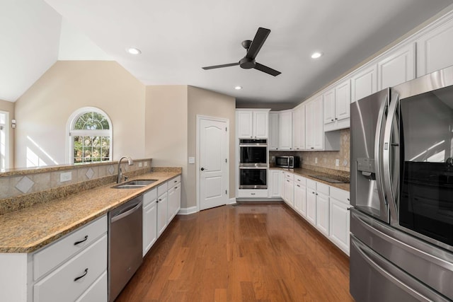 kitchen with dark wood-style flooring, stainless steel appliances, decorative backsplash, white cabinetry, and a sink