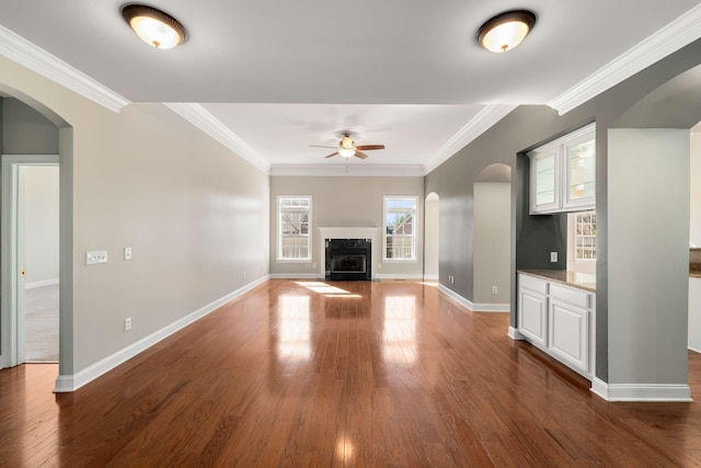 unfurnished living room featuring a fireplace with flush hearth, ornamental molding, and wood finished floors