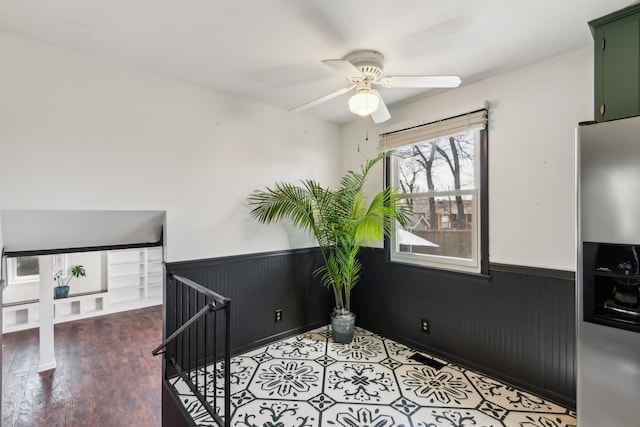 interior space featuring light wood-style flooring, wainscoting, and a ceiling fan