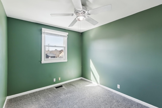 carpeted empty room featuring baseboards, visible vents, and ceiling fan