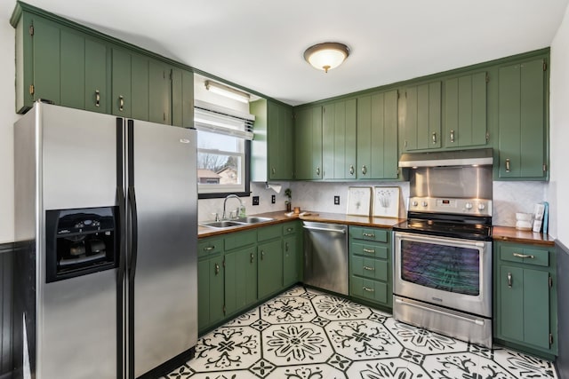 kitchen featuring under cabinet range hood, appliances with stainless steel finishes, backsplash, and a sink