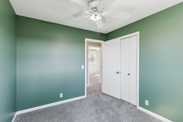 unfurnished bedroom with ceiling fan, a closet, baseboards, and carpet flooring