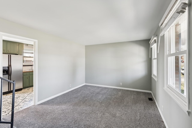 spare room featuring light carpet, plenty of natural light, visible vents, and baseboards