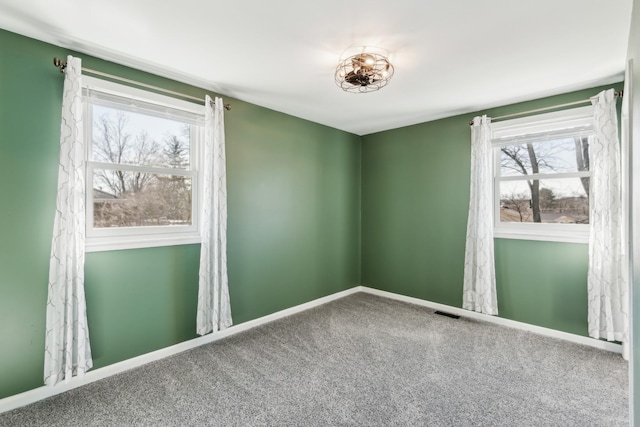 carpeted spare room featuring visible vents and baseboards