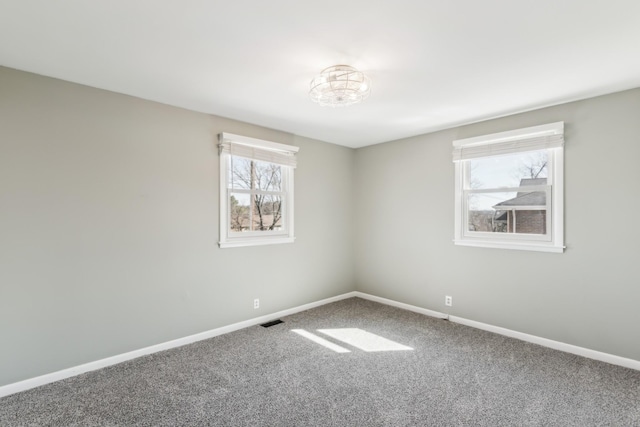 carpeted empty room featuring baseboards and visible vents