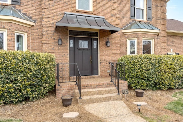 entrance to property featuring a standing seam roof, metal roof, and brick siding