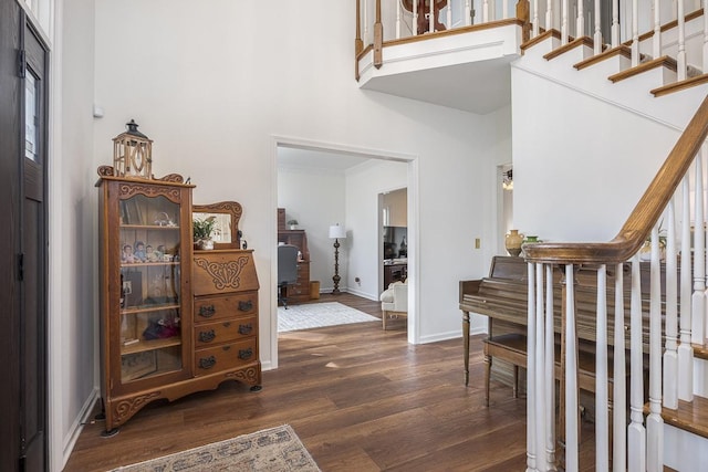 entryway with dark wood-style flooring, a towering ceiling, stairway, ornamental molding, and baseboards