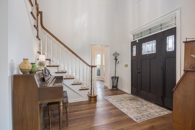 entryway featuring dark wood-type flooring, baseboards, a high ceiling, and stairs