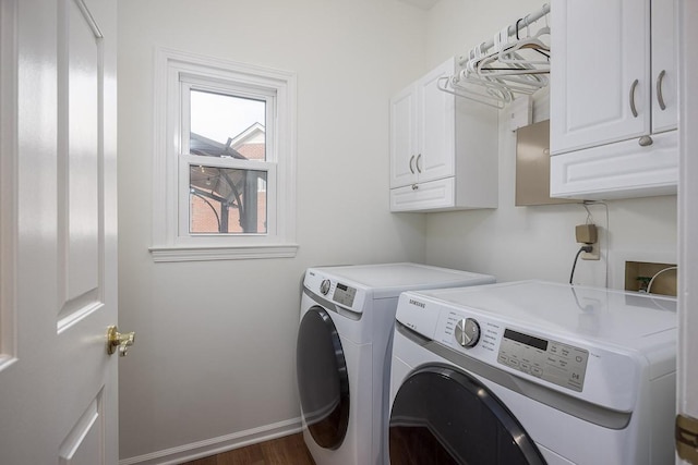 laundry area featuring washing machine and dryer, cabinet space, baseboards, and wood finished floors