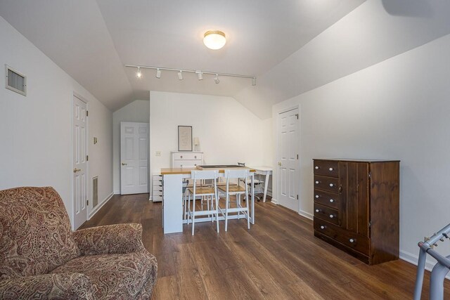 dining room featuring baseboards, visible vents, wood finished floors, vaulted ceiling, and track lighting