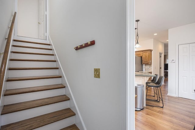 stairs featuring baseboards, wood finished floors, and recessed lighting