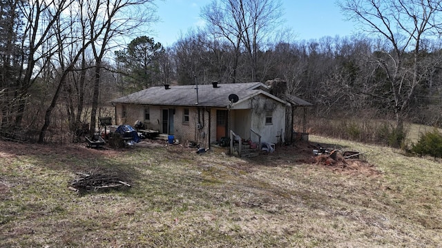 back of house with entry steps, brick siding, and a wooded view