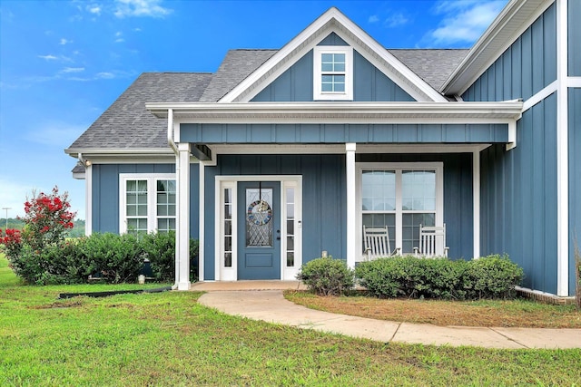 entrance to property featuring a shingled roof, board and batten siding, a porch, and a lawn