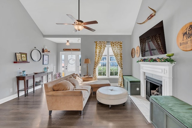 living room featuring a fireplace, vaulted ceiling, baseboards, and wood finished floors