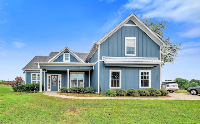 view of front facade with board and batten siding, a front yard, and a shingled roof