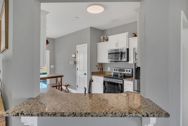 kitchen with stone countertops, baseboards, a peninsula, stainless steel appliances, and white cabinetry