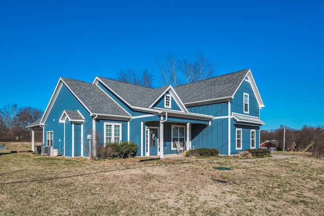 view of front facade featuring a front lawn, cooling unit, and roof with shingles