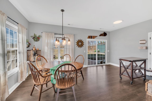 dining area featuring dark wood-style floors, a chandelier, and baseboards