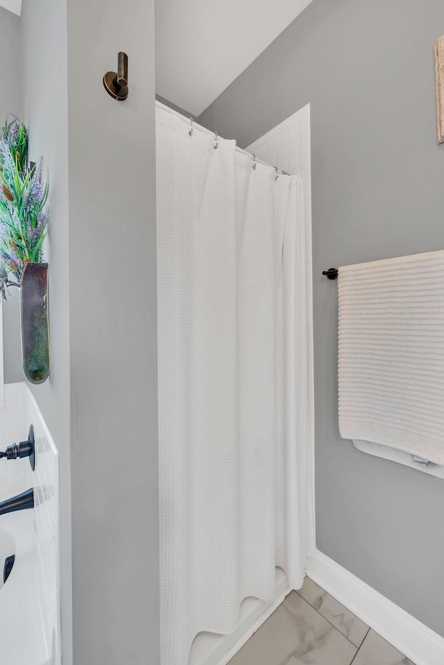 bathroom featuring marble finish floor, a shower with curtain, a bath, and baseboards