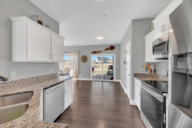 kitchen with light stone counters, dark wood-style flooring, stainless steel appliances, white cabinetry, and a sink