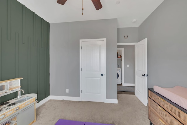 bedroom featuring light carpet, washer / dryer, ceiling fan, and baseboards