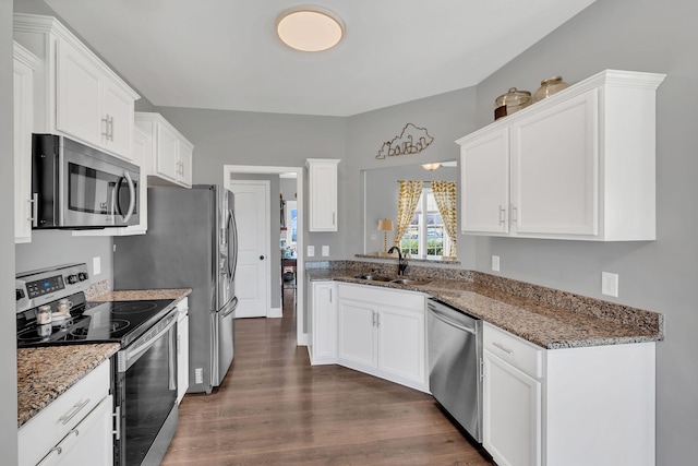 kitchen featuring appliances with stainless steel finishes, dark wood-type flooring, a sink, and white cabinetry