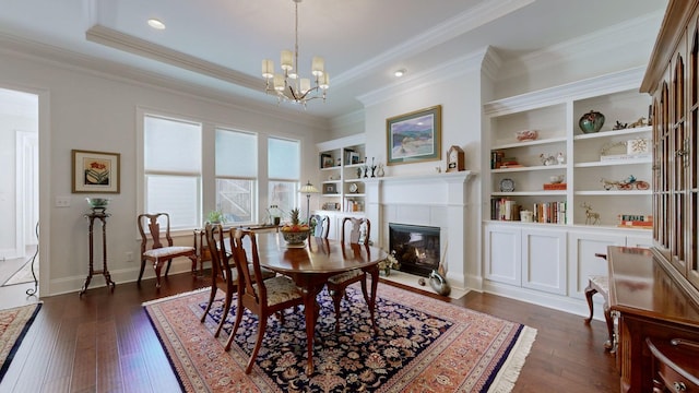 dining room with a chandelier, ornamental molding, a tile fireplace, and dark wood finished floors