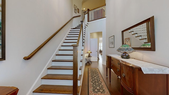 stairway featuring a towering ceiling and wood finished floors