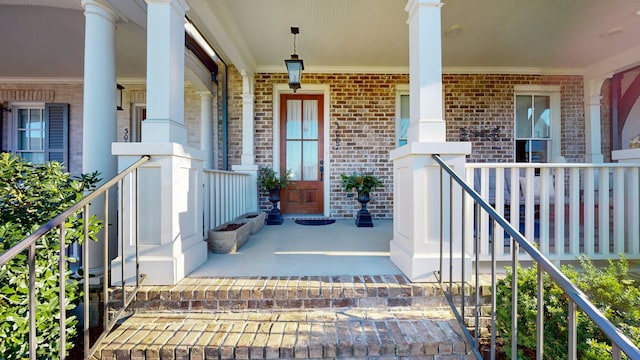 entrance to property featuring covered porch and brick siding