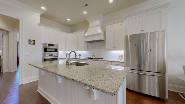 kitchen featuring dark wood finished floors, stainless steel appliances, custom range hood, white cabinets, and a sink