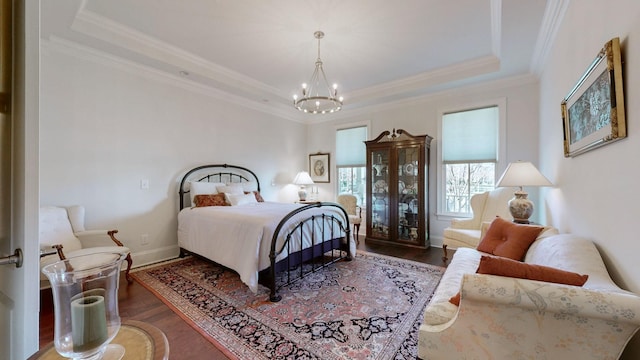 bedroom with baseboards, a tray ceiling, wood finished floors, and ornamental molding