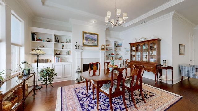 dining space featuring dark wood-style floors, a notable chandelier, visible vents, ornamental molding, and a tile fireplace