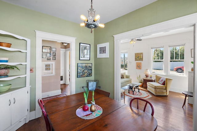 dining room featuring dark wood-style flooring, baseboards, and an inviting chandelier