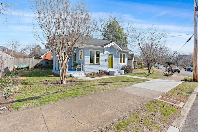 bungalow-style home with a front yard and fence