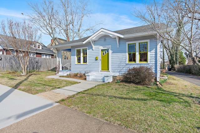 bungalow-style house featuring a front lawn, roof with shingles, and fence