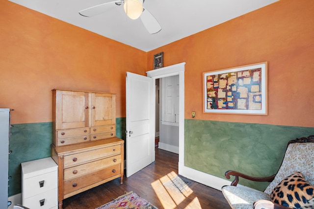 living area with baseboards, dark wood finished floors, and a ceiling fan