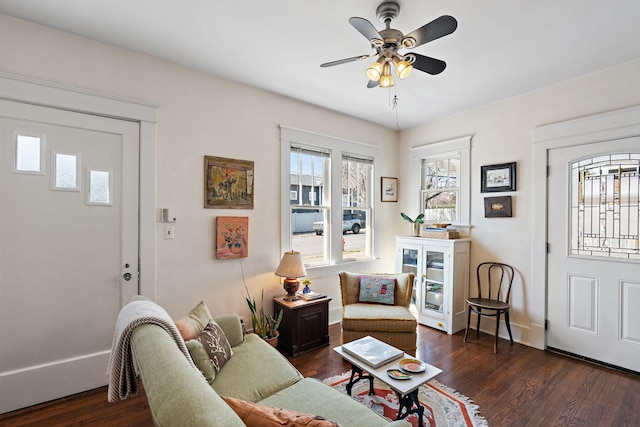 living area featuring dark wood-type flooring, ceiling fan, and baseboards