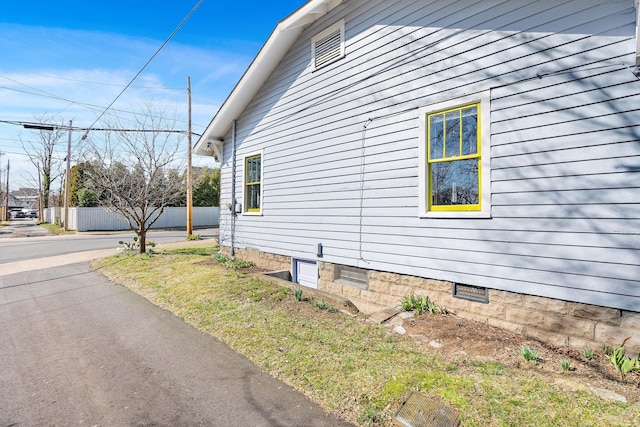 view of side of property with crawl space and fence