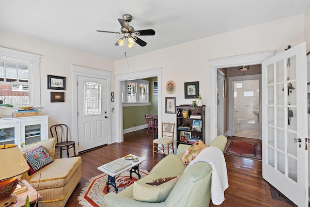 living room featuring ceiling fan, baseboards, and wood finished floors