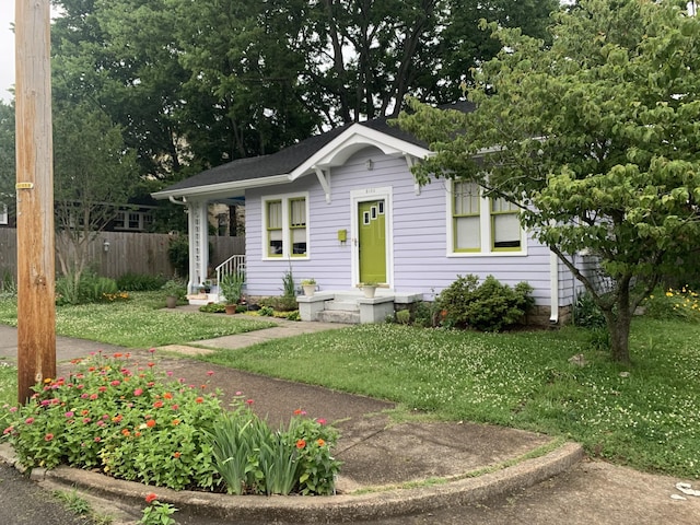 bungalow-style house with fence and a front lawn