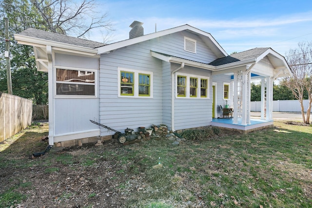 rear view of property with a lawn, a patio, a chimney, roof with shingles, and fence