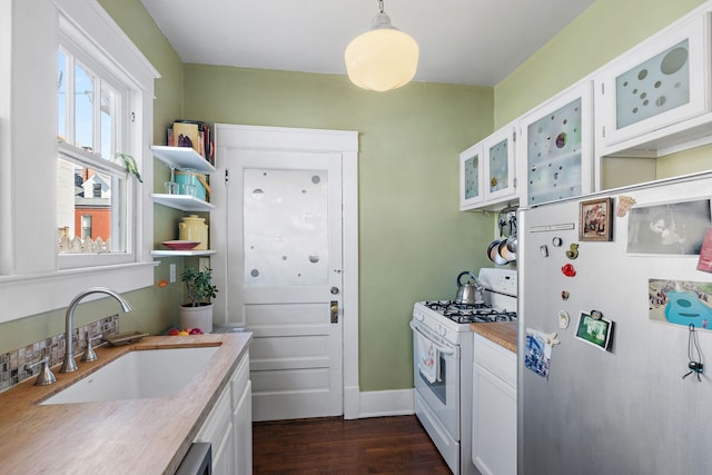 kitchen featuring white cabinets, refrigerator, gas range gas stove, light countertops, and a sink