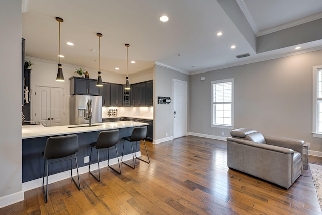 kitchen with dark wood finished floors, stainless steel fridge with ice dispenser, visible vents, a peninsula, and a kitchen bar