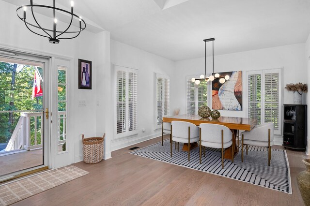 dining space featuring wood finished floors, visible vents, plenty of natural light, and an inviting chandelier