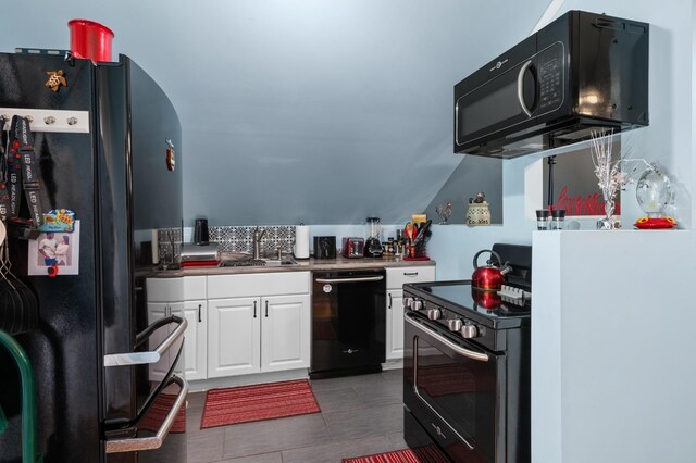 kitchen featuring black appliances, white cabinetry, a sink, and dark tile patterned flooring