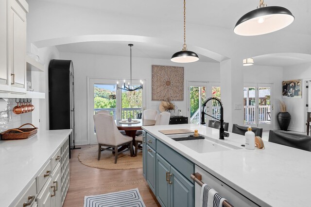 kitchen featuring light countertops, light wood finished floors, a sink, and blue cabinets