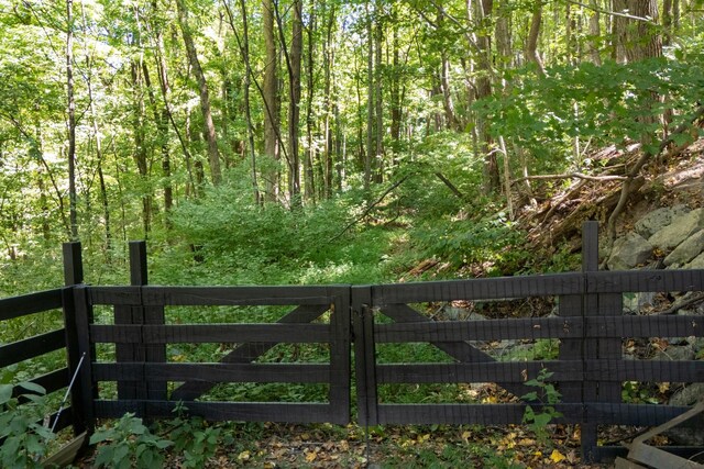 view of gate with fence and a view of trees