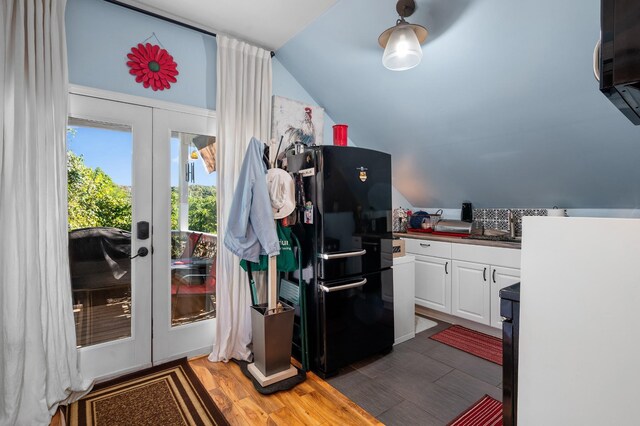 kitchen with french doors, lofted ceiling, freestanding refrigerator, white cabinets, and light wood-type flooring