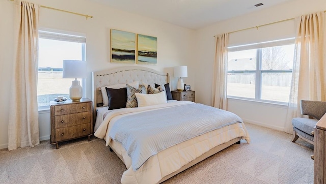 bedroom featuring light carpet, multiple windows, and baseboards